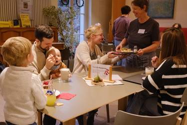 Frau bringt Tablet einem Gast an den Tisch